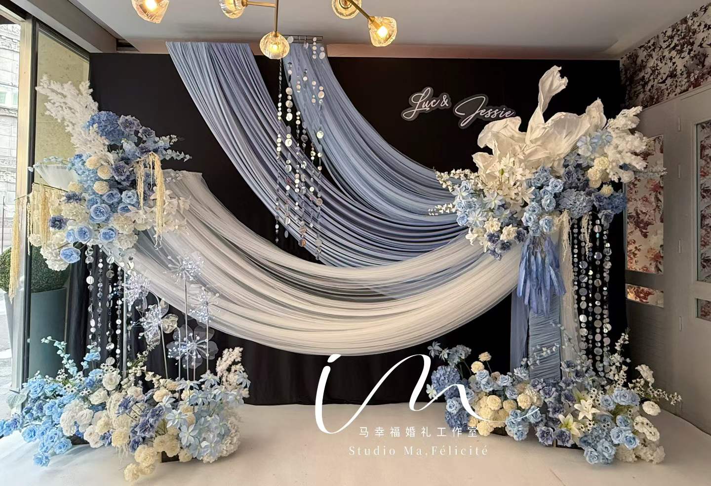 Dusty-blue draped ceremony backdrop with hydrangeas and crystal strands